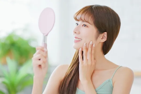 鏡で自分の顔を見る女性